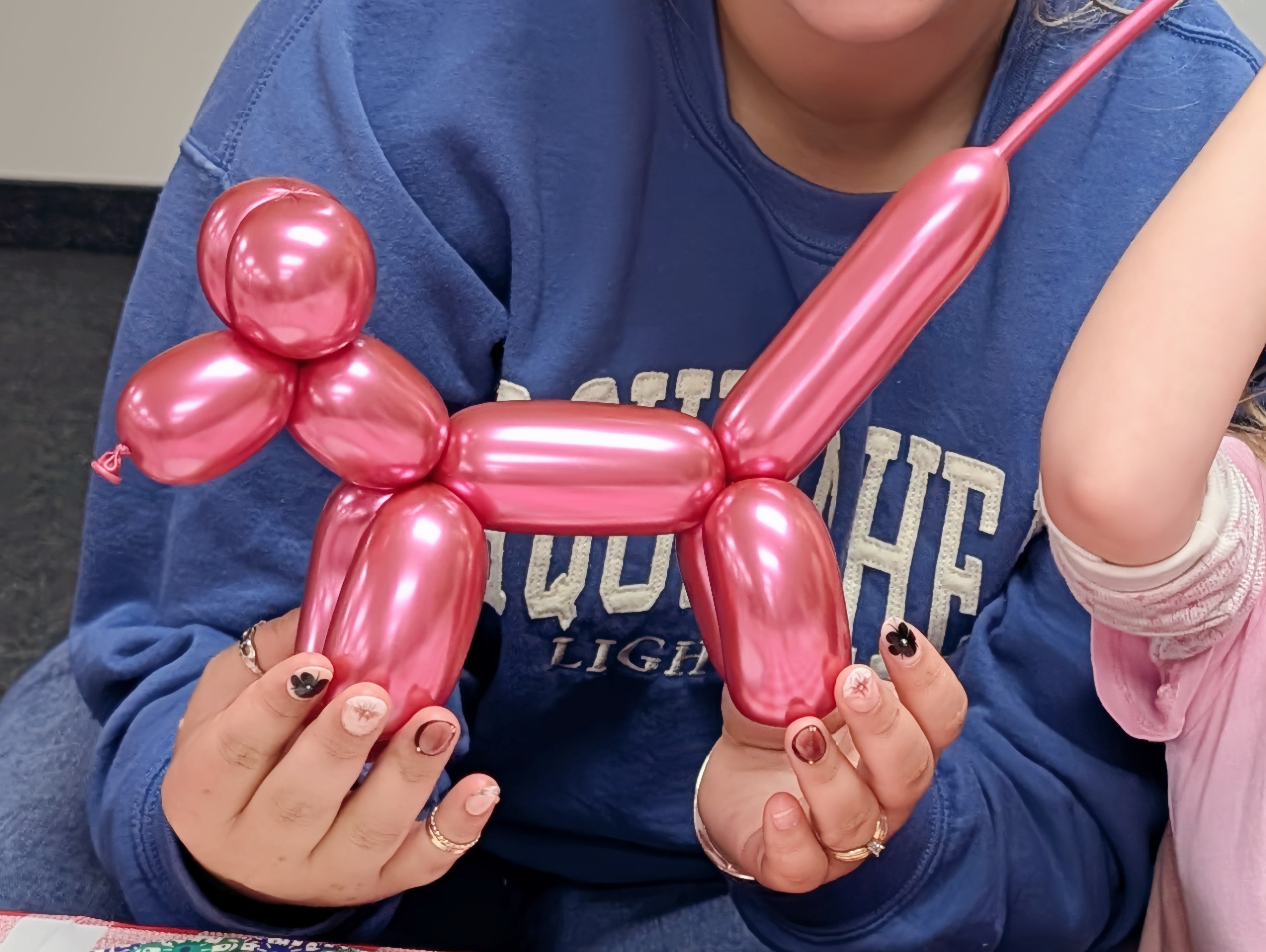 Child holding a pink balloon animal dog