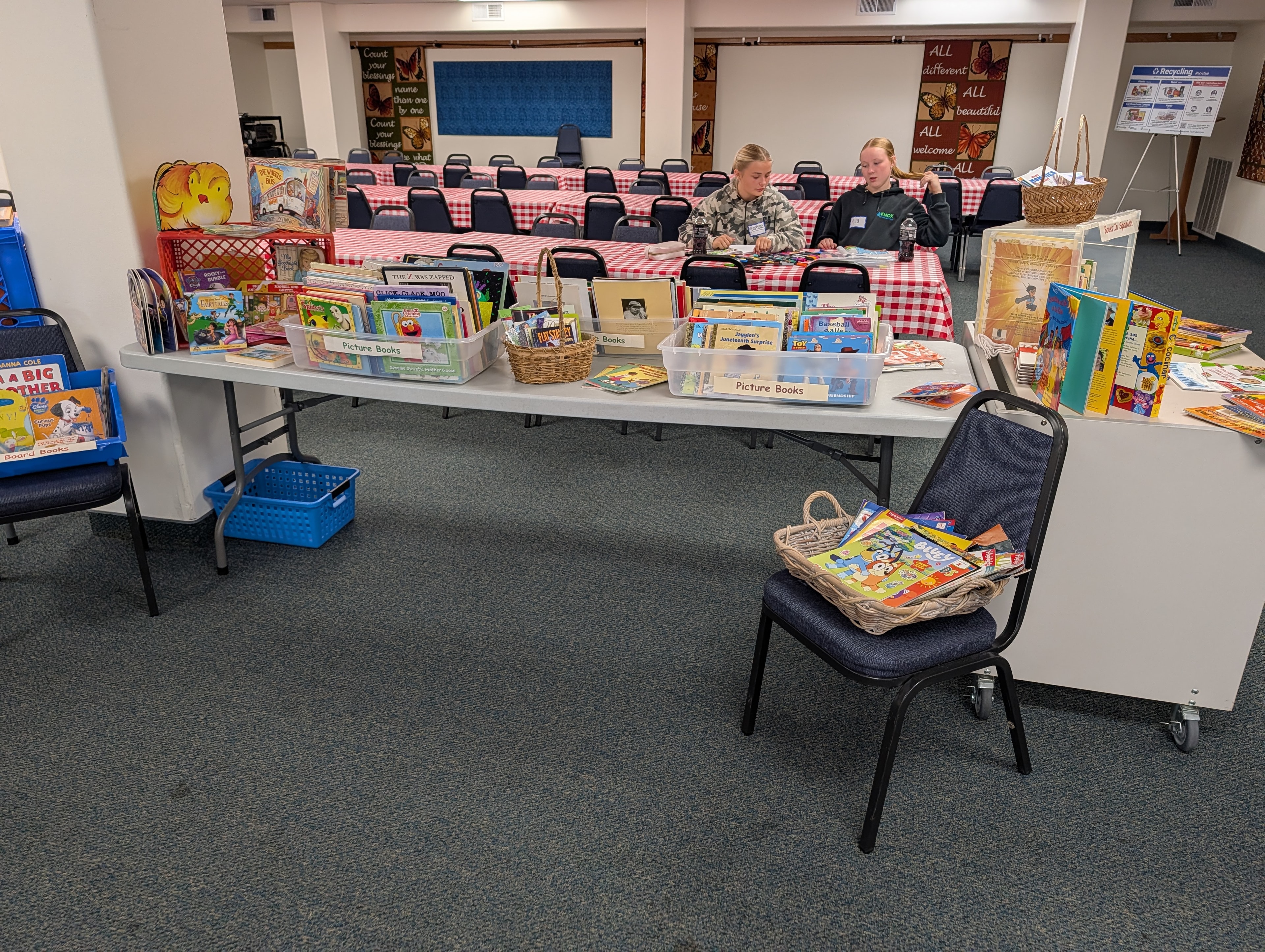 Volunteers staffing a free book table with picture books and board books