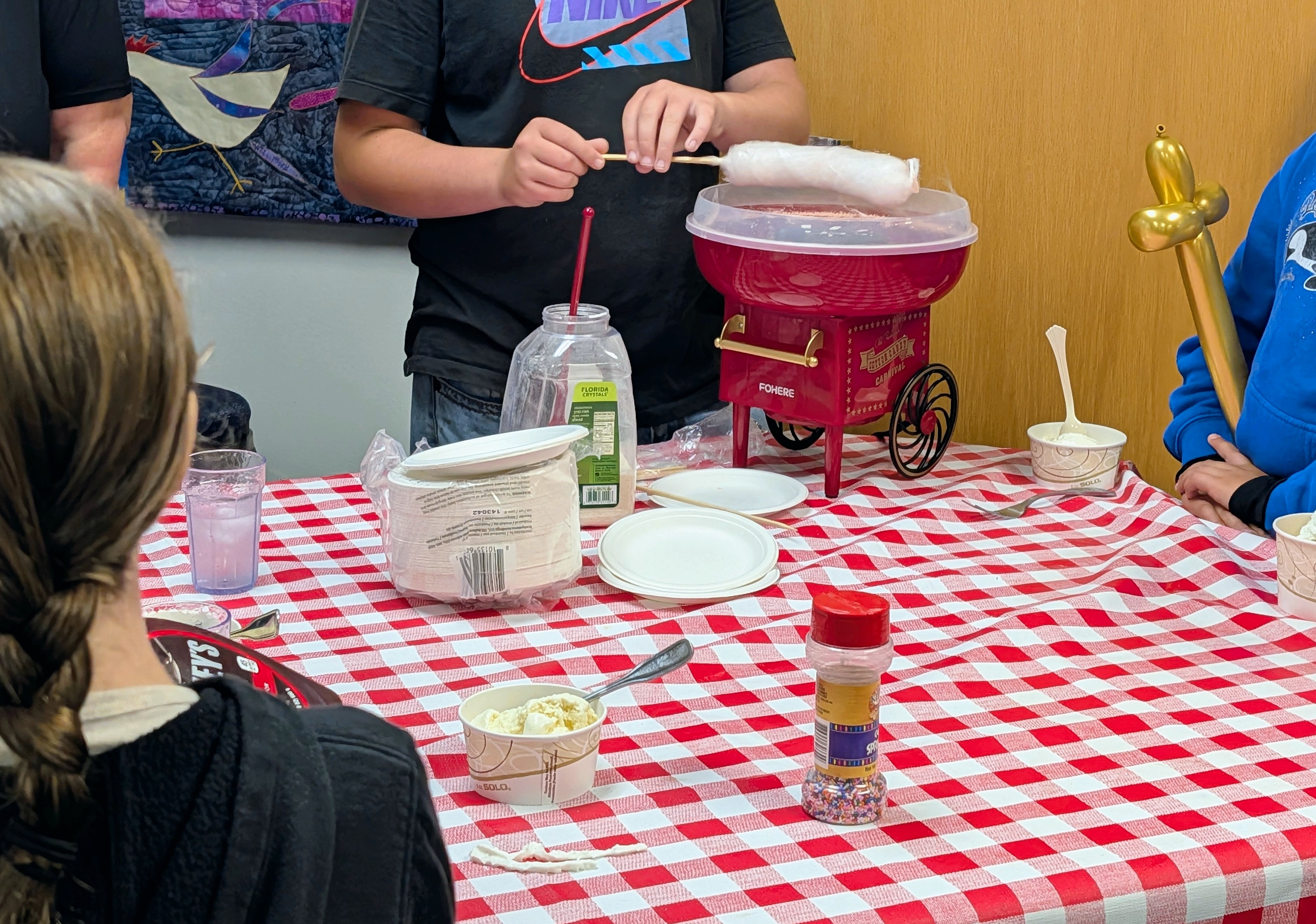 Kids making cotton candy at a carnival machine